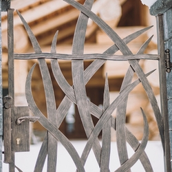 Geschmiedete Pforte mit Grasmuster als Teil der außergewöhnlichen Umzäunung der Hütte – künstlerische Tore und Zäune 