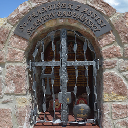 Schmiedeeisernes Denkmal der Heiligen mit Attributen auf dem Gitter. St. Franz von Assisi  Tau-Zeichen, St. Antonius von Padua  Brot