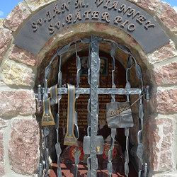 Monument forg des saints avec des attributs sur les grilles. Saint Jean-Marie Vianney, Saint Padre Pio