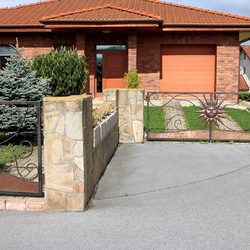 An artistic fence of a family house - a wrought-iron gate and a small gate