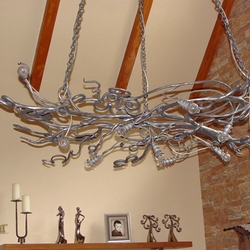 Lustre d’intérieur artisanal en acier poncé, crée de branches-volutes, suspendu par les chaînes. 