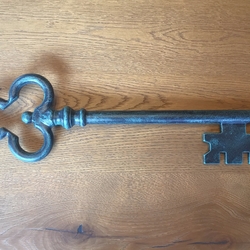 A wrought iron key in green patina