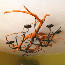 Plafonnier de style rustique, la pièce forgée en forme de chandelier de campagne mariée à la branche d’arbre